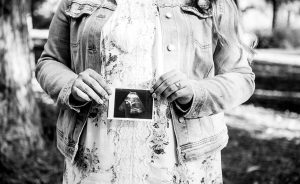 woman holds the ultrasound of her unborn child who was wrongfully killed in a car accident