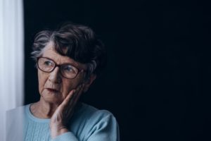 woman who experienced sexual abuse and nursing home abuse injuries in a nursing home sits alone in a dark room, wondering if medicare will help her